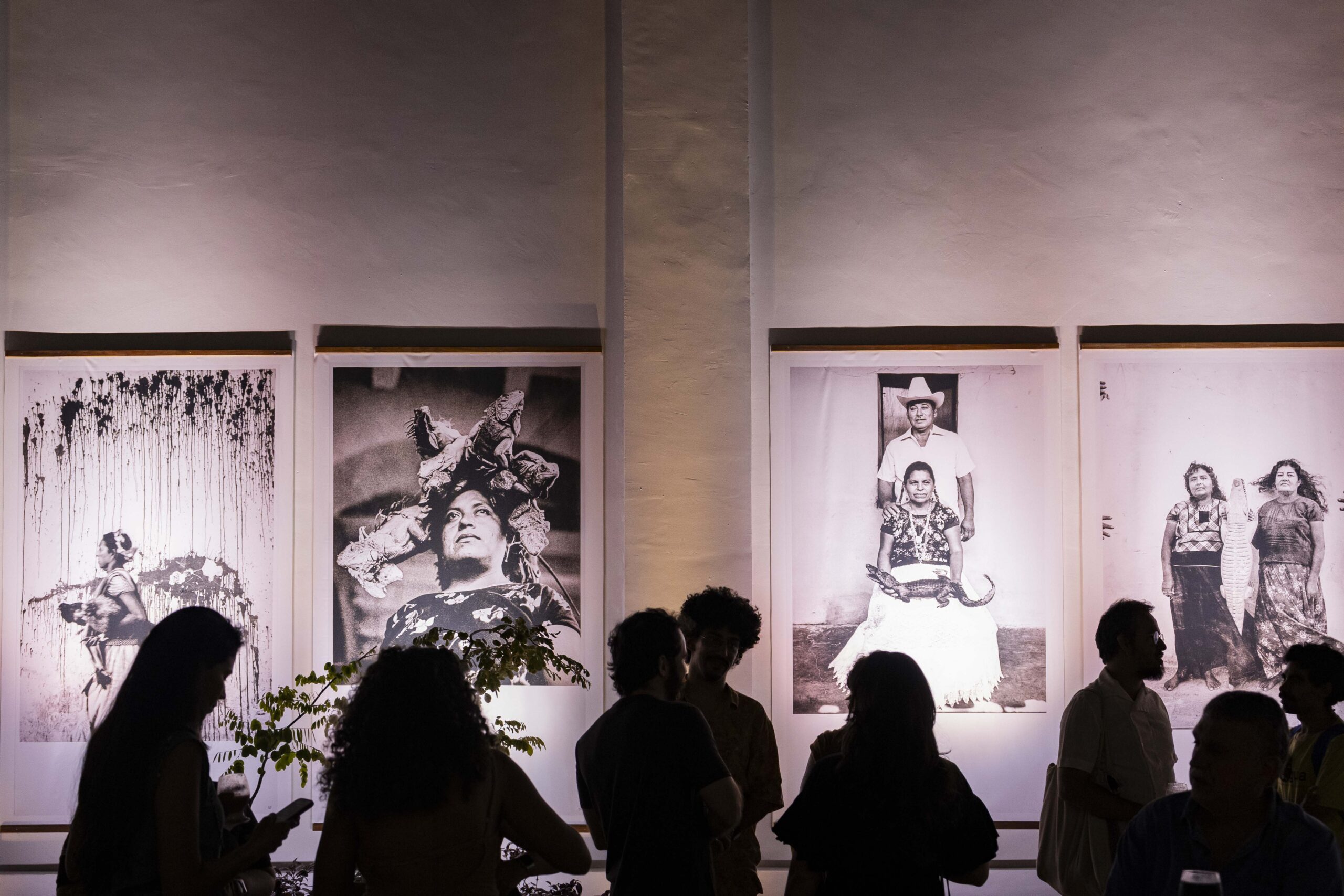 A imagem mostra um Evento na Pinacoteca do Ceará, com pessoas apreciando obras de arte em um espaço iluminado e moderno.